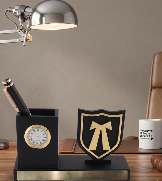 Decorative desk set with clock, pen holder, and emblem on a wooden surface.